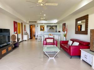 a living room with a red couch and a table at Kata Seaview Escape - 1BR Luxury Apartment 90sqm in Phuket