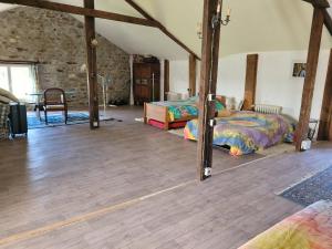 a bedroom with two beds and a wooden floor at Ferme fruitière zéro traitement in Ernée