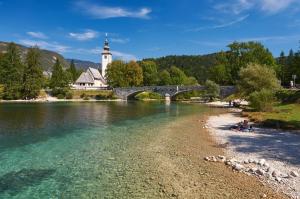a bridge over a river with people sitting on the shore at Ani's Pearl in Bled
