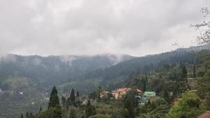 a town in the middle of a mountain with trees at Rainbow Guest House in Sonāda