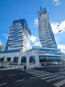 two tall buildings in a city with a person walking in front at Park View Olszynki Park in Rzeszów