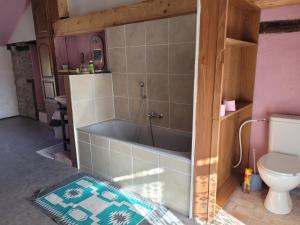 a bathroom with a bath tub and a toilet at Ferme fruitière zéro traitement in Ernée