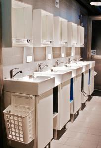 a row of sinks in a public bathroom at Cavemen Hostel Taipei Station Youth Branch in Taipei