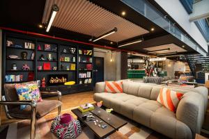 a living room with a couch and a book shelf at Moxy Paris La Villette in Paris