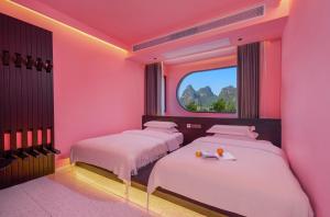 two beds in a pink room with a window at Yangshuo B&G Hotel-Exclusive location,Roof Top Viewing Terrace,Seasonal swimming pool,Free Self-Service Laundry & Drying, Entrance Ticket Serivce, Local Trip plan,E-Scooter& English Customer Service in Yangshuo +72 photos