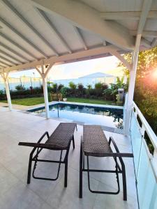 a patio with a table and chairs next to a swimming pool at Villa Gommier - 3 chambres, 3 sdb, piscine in Le Diamant