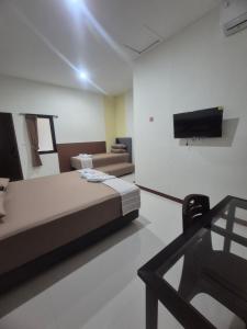 a room with a bed and a tv on the wall at ERCA Yogyakarta in Yogyakarta