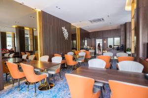 a restaurant with orange chairs and tables in a room at Carista Hotel in Vientiane