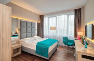 a bedroom with a bed and a desk and a television at Hollywood Media Hotel am Kurfürstendamm in Berlin