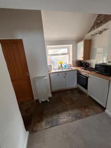 a small kitchen with white cabinets and a window at Mundesley Cosy cottage in Mundesley