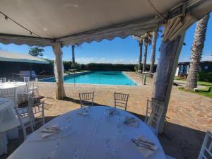 a table under a pavilion with a swimming pool at CHouse Golf MarediRoma in Ardea