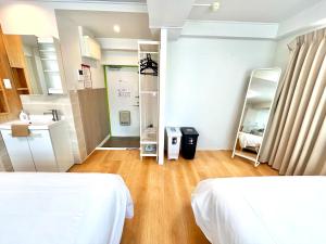 a room with two beds and a bathroom with a sink at Rhodes Kagurazaka in Tokyo