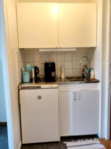 a small kitchen with white cabinets and a sink at Sun life room in Stockholm