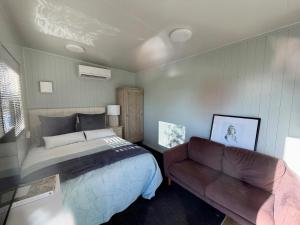 a bedroom with a bed and a couch at Benrose Stables Cottage in Palmerston North