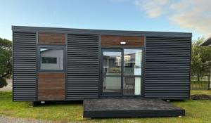 a small black tiny house sitting on the grass at Benrose Stables Cottage in Palmerston North