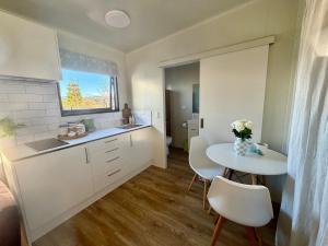 a kitchen with a sink and a table with chairs at Benrose Stables Cottage in Palmerston North