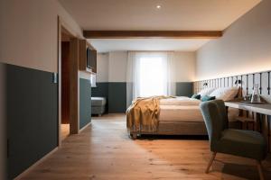 a bedroom with a bed and a desk and a chair at Bella Posta Hotel in Soprabolzano +139 photos