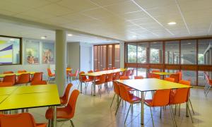 a cafeteria with yellow tables and orange chairs at Centre International de Séjour André Wogenscky in Saint-Étienne
