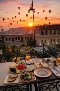 a table with plates of food on a balcony with the sunset at Cratus Stone Palace in Göreme