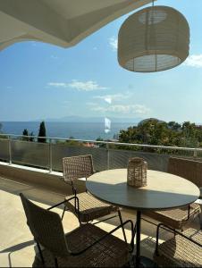 a table and chairs on a balcony with a view of the ocean at Olivia -Ελιά in Paleo Tsifliki