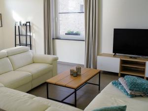 a living room with a white couch and a tv at Hof ter Eversam in Alveringem
