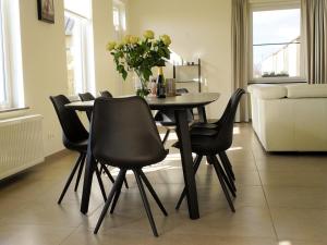 a dining room table with black chairs and a vase of flowers at Hof ter Eversam in Alveringem