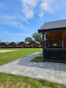 a building in front of a field with houses at By The Way - domki nad morzem in Paprotno
