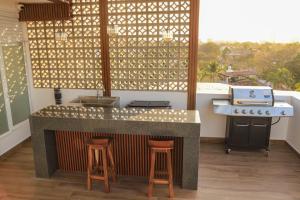a kitchen with a counter with a stove and stools at Monbelt Luxury Apartment with Rooftop Jacuzzi in Puerto Vallarta +5 photos