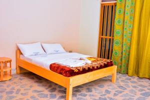 a bed with two pillows on top of it at Bwindi Breeze Lodge in Kisoro