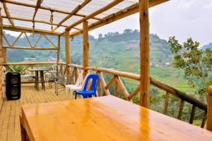 a wooden deck with a table and chairs and a view at Bwindi Breeze Lodge in Kisoro