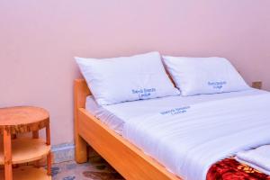 a bed with white sheets and pillows on it at Bwindi Breeze Lodge in Kisoro