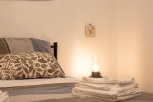 a bed with a lamp and a stack of towels at La Cortese, cuore barocco in Noto