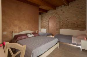 a bedroom with two beds and a brick wall at B&B Olmo in Saludecio +45 photos