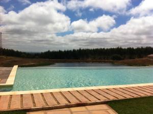 a large pool of water with a wooden deck at Casas de Miróbriga in Santiago do Cacém