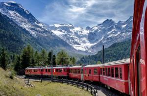 a red train is traveling through the mountains at Poschiavo Maiensäss auf 1400m in Le Prese +37 photos