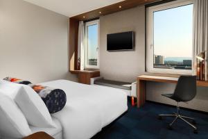 a hotel room with a bed and a desk and window at Aloft by Marriott Stuttgart in Stuttgart