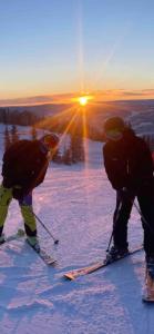 two people on a ski slope with the sun in the background at Tiny house on wheels with great views Sjusjøen Minihus med utsikt Sjusjøen in Mesnali