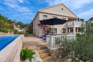 a house with an umbrella next to a swimming pool at Apartments - Villa Ana in Milna