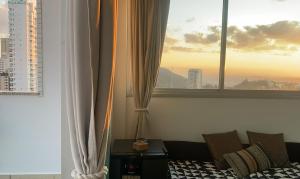 a living room with a couch and two windows at Cobertura Espetacular no Belvedere com Jacuzzi in Belo Horizonte +19 photos