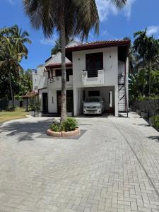a house with a palm tree in the driveway at Perera Tree Villa in Ja-Ela