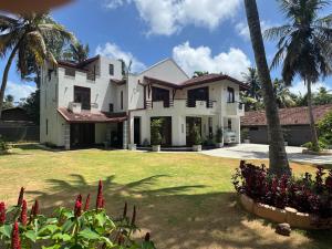a white house with palm trees and a yard at Perera Tree Villa in Ja-Ela
