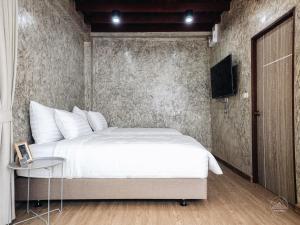a bedroom with a bed and a tv on a wall at El Vaso Resort in Chanthaburi