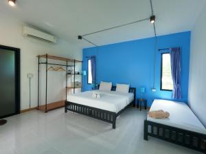 a bedroom with two beds and a blue wall at Koh Kood Chalet in Ban Hin Dam +1 photo