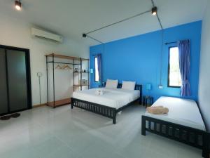 a bedroom with two beds and a blue wall at Koh Kood Chalet in Ban Hin Dam