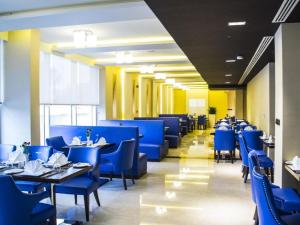 a dining room with blue chairs and tables at Gulf Pearls Hotel in Doha