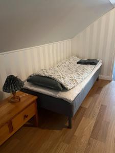 a small bed in a room with a wooden table at Gästhus i Västanbyn, Sandviken in Sandviken +5 photos