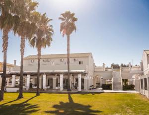 a large white building with palm trees in the yard at Ionian Blue Beach Hotel - Adults Only in Kavos