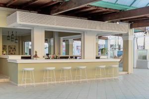 a bar in a building with stools around it at Ionian Blue Beach Hotel - Adults Only in Kavos