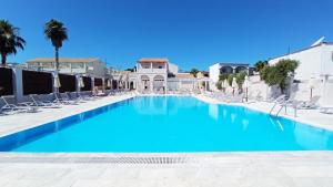 a large swimming pool with chairs and blue water at Ionian Blue Beach Hotel - Adults Only in Kavos