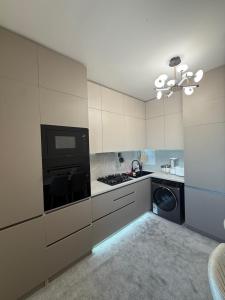 a kitchen with white cabinets and a stove top oven at Olmazor Comfort in Qoraqamish